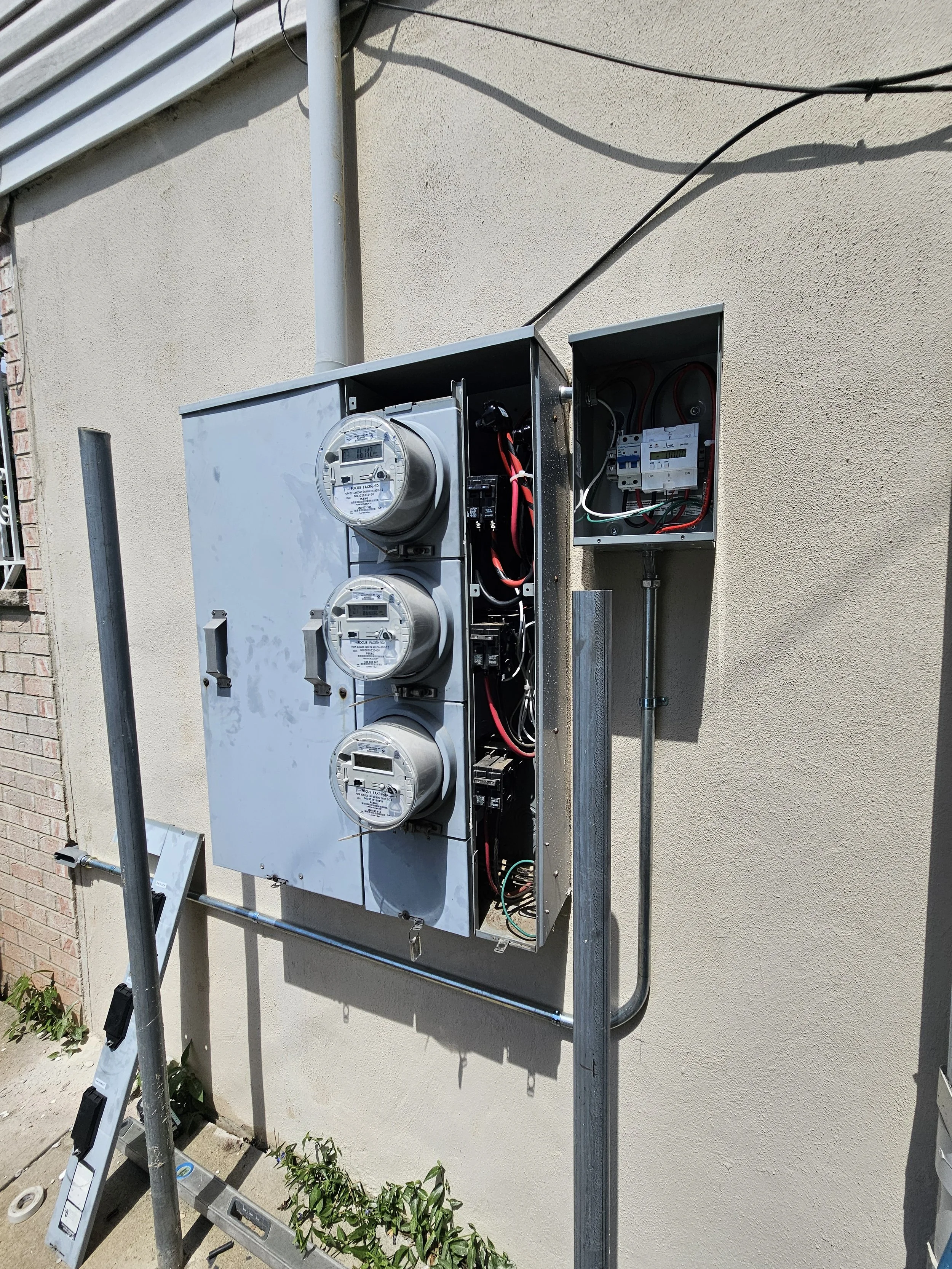 Residential exterior electrical meter box with three digital meters, wiring, and electrical components needed for electrical service